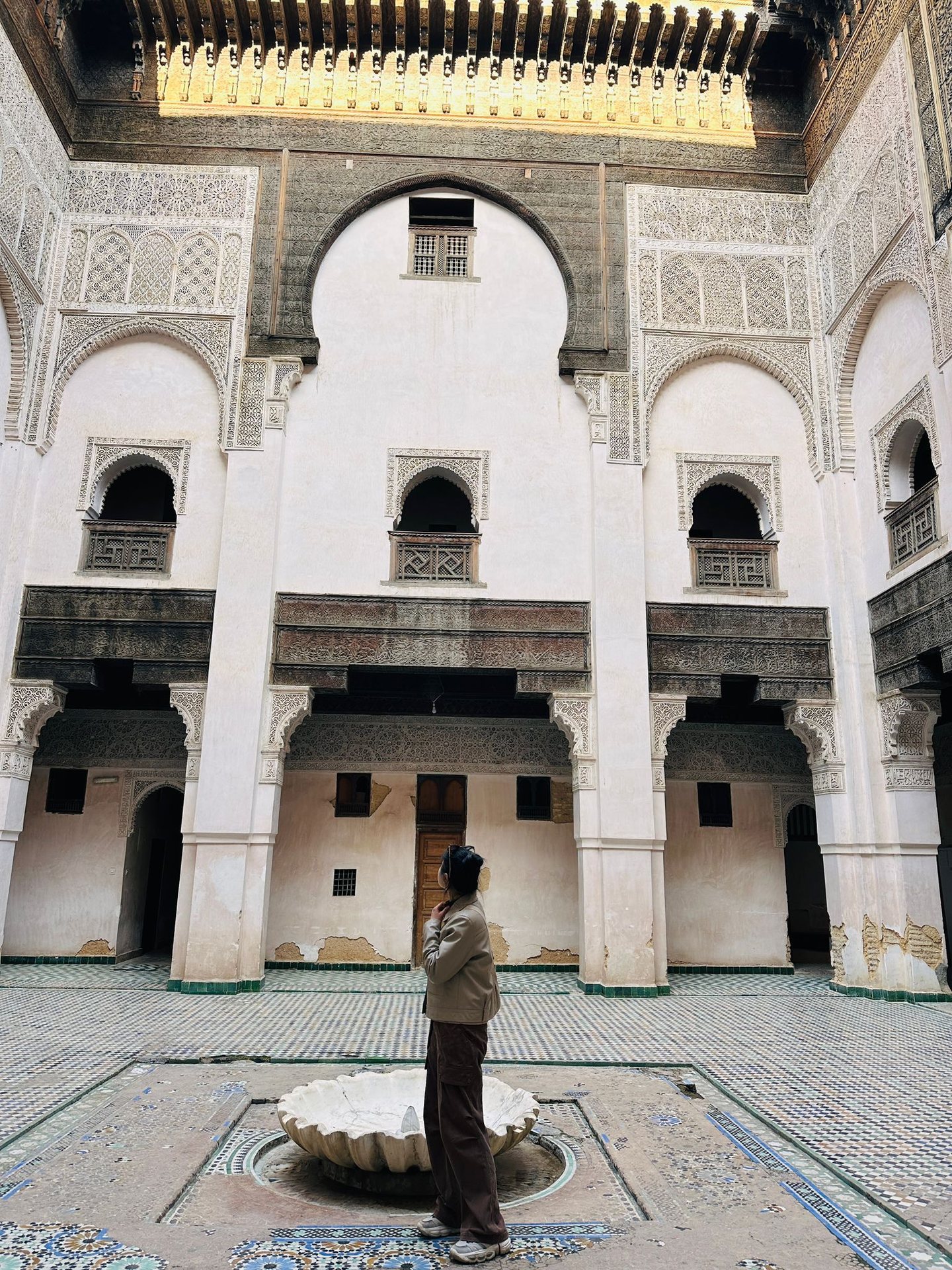 Traveler admiring the ornate courtyard of a Fes medersa