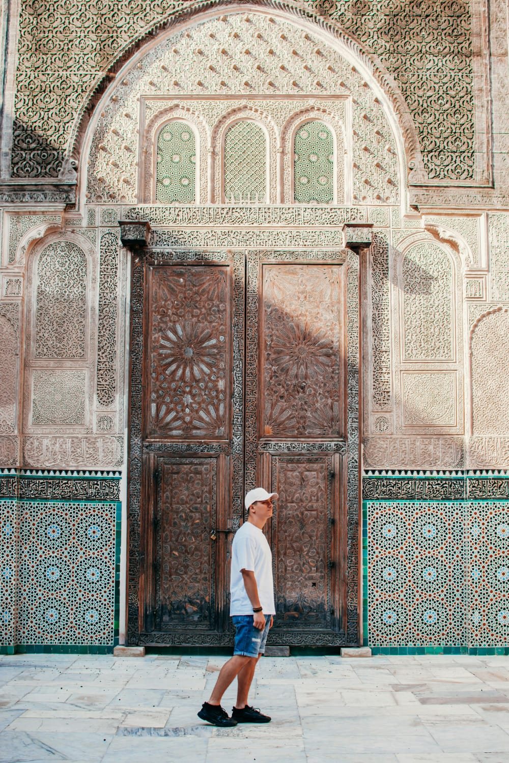 Traveler beside an ornate carved door in Marrakech